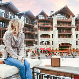 A woman sitting on a bench looking back at The Ranahan by Welks Resorts in Breckenridge, CO